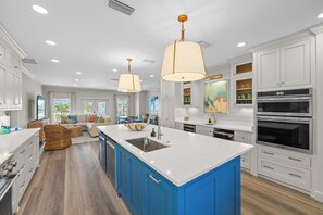 A spacious kitchen with white cabinets, blue accents, a large island, and modern appliances. - New Beach Listing! Harmony Key - 8BR, 5Bath, Private Beach, Pool, Spa! (Pensacola)