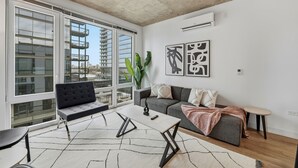Ein modernes Wohnzimmer mit einer Couch, einem Couchtisch und einem großen Fenster mit Blick auf die Stadt.