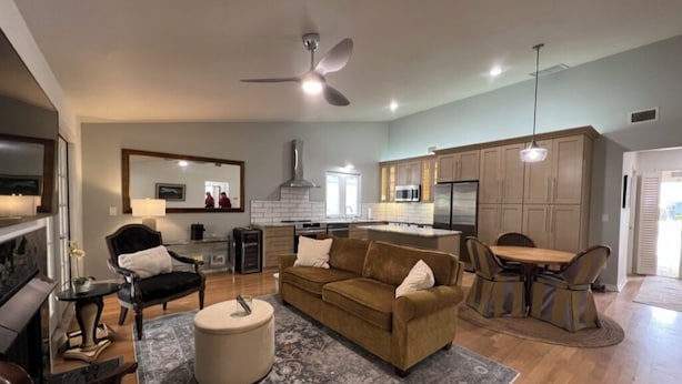 Eine moderne Küche mit Kochinsel, Essbereich mit Tisch und Stühlen, Sofa und Deckenventilator.