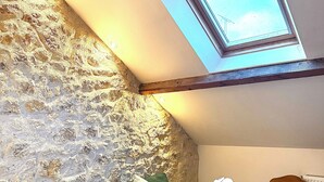 A cozy living room with a stone wall, a green sofa with cushions, a wooden coffee table, and a brown armchair. - Le maréchal Deluxe T2 Tours centre-Nationale- Vieux tours (Tours)