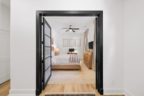 A bedroom with a bed, bedside tables, a dresser, a ceiling fan, and framed pictures on the wall. - Walk to Mercedes-Benz Stadium - 4BR + Parking - Downtown ATL (Atlanta)
