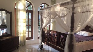 A four-poster bed with a canopy, a wooden dresser, and a mirror. - 3 Bedroom Villa with the view of Bentota river. (Aluthgama)