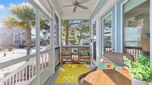 A covered porch with a ceiling fan, wooden chairs, a wicker sofa, and a yellow rug. - Pet Friendly Beach House - Salt Therapy (Port St. Joe)