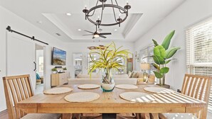 A spacious dining area with a wooden table, woven placemats, and a central vase with plants. - Pet Friendly Beach House - Salt Therapy (Port St. Joe)