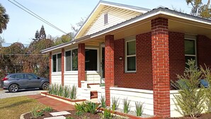 A single-story house with a brick facade, a covered porch, and a small garden area with plants and stepping stones. - Walk to Historic St. Augustine | Guest Favorite (St. Augustine)