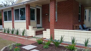 A house with a brick exterior, a front porch, and a small garden area with stepping stones and plants. - Walk to Historic St. Augustine | Guest Favorite (St. Augustine)
