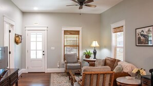 A living room with a ceiling fan, a sofa, a chair, a TV, and a door marked "EXIT". - Walk to Historic St. Augustine | Guest Favorite (St. Augustine)