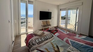 A bedroom with a large bed, a flat-screen TV, and a balcony with a view of the sea. - Villa in Estepona with panoramic views and a private pool. (Estepona)
