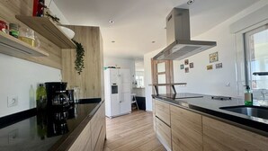 A modern kitchen with wooden cabinetry, a black countertop, and a built-in oven. - Villa in Estepona with panoramic views and a private pool. (Estepona)
