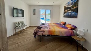 A modern bedroom with a bed, a bench, a TV, and a painting. - Villa in Estepona with panoramic views and a private pool. (Estepona)