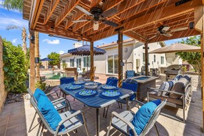 Une terrasse extérieure dotée d’un espace salon couvert, d’une piscine et d’un barbecue.