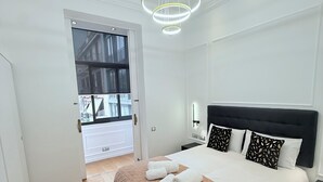 Quarto moderno com uma cama grande, mesa de cabeceira e luminária no teto.