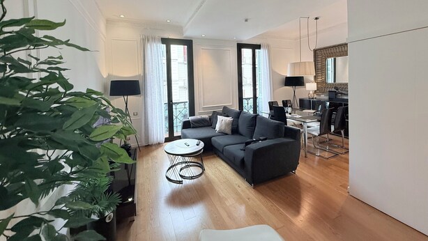 Uma sala de estar moderna com um sofá, uma mesa de centro e uma área de jantar com cadeiras e mesa.