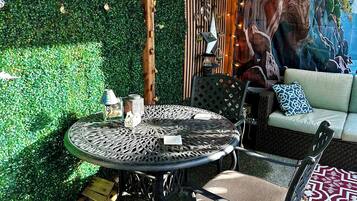 A patio area with a round metal table, chairs, and a sofa.