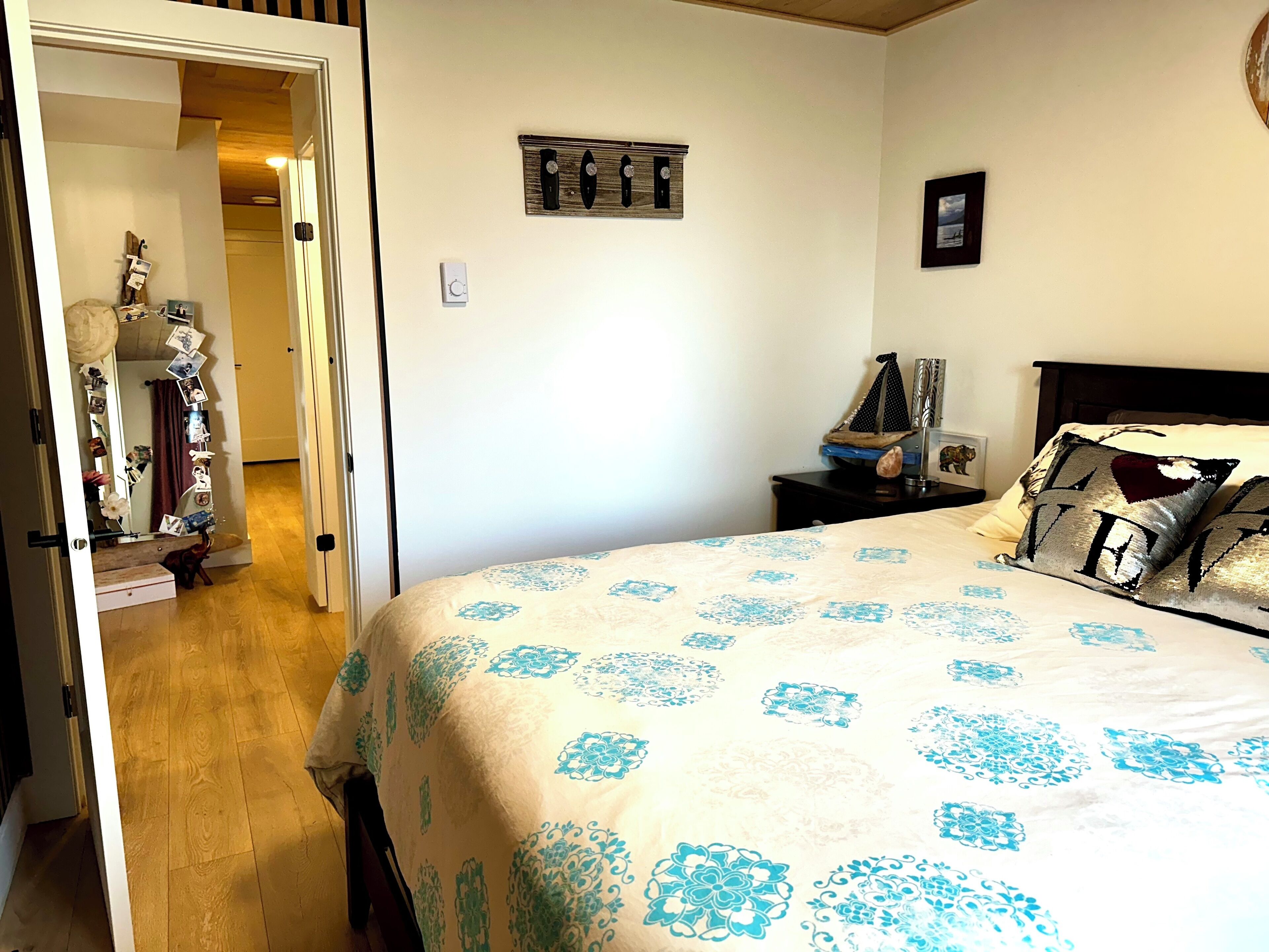 Une chambre à coucher comprenant un lit, une commode, une table de chevet, un miroir et une horloge murale.