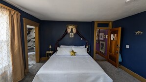 A bedroom with a large bed, a canopy, a bedside table, and a wardrobe.