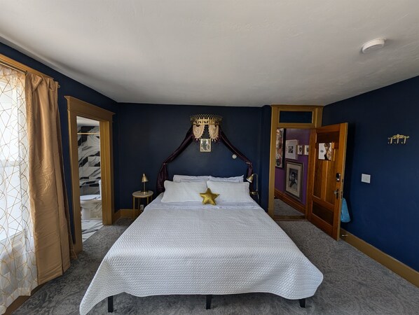 A bedroom with a large bed, a canopy, a bedside table, and a wardrobe.