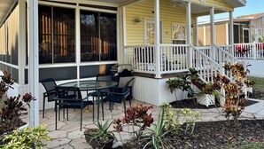 A covered patio with outdoor seating, a small table, and potted plants.