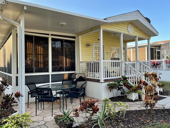 Un patio cubierto con mobiliario exterior, una pequeña mesa y plantas en macetas.