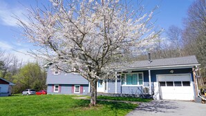 A house with a garage, a tree in front, and two parked cars. - Cozy River Valley Family Retreat w/ Fireplace, Games & Serene Deck (Sparrow Bush)