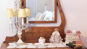 Une commode en bois avec un miroir, un chandelier, une figurine et un chemin de table en dentelle.