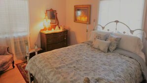 Une chambre à coucher comprenant un lit, une commode, une chaise, un lustre et un tableau encadré accroché au mur.