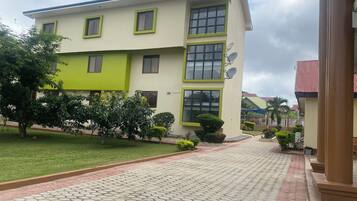 A two-story building with a green and white facade, satellite dishes, and a paved walkway leading to the entrance.