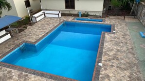 A rectangular swimming pool with a tiled deck surrounding it. - Excelsa Lodge (Ejisu)