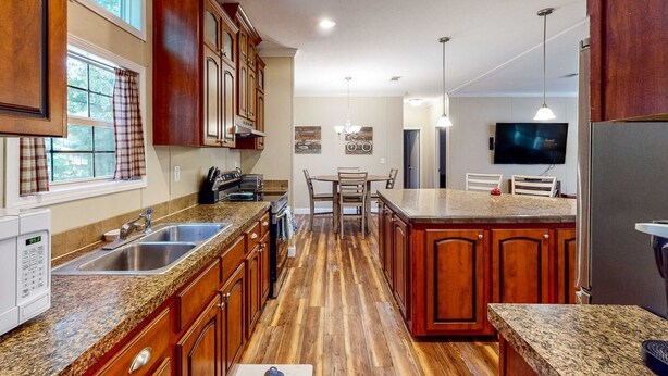 A kitchen with wooden cabinets, granite countertops, a built-in island, and a dining area with chairs. - Cozy Williston Retreat Near WEC, HITS and Local Springs-Perfect for Show Stays 🐴 (Williston)