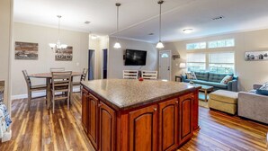 A spacious living area with a kitchen island, wooden flooring, and a sofa. - Cozy Williston Retreat Near WEC, HITS and Local Springs-Perfect for Show Stays 🐴 (Williston)