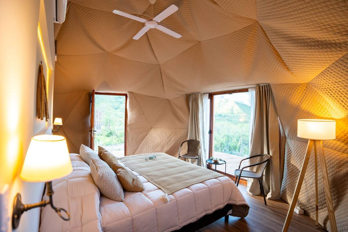 Une chambre à coucher avec un lit, une chaise, une lampe et un ventilateur de plafond.