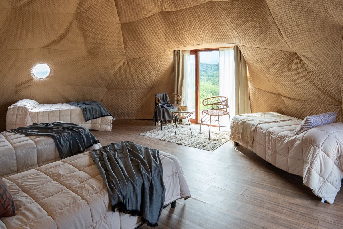 A cozy, tent-like room with two beds, a small table, and a chair.