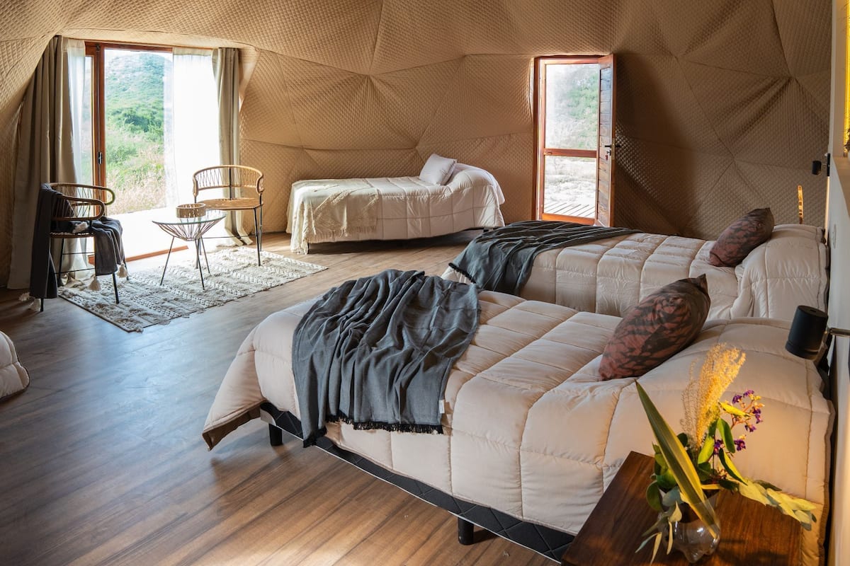 Une chambre confortable avec un lit, une chaise et une petite table sur laquelle est posé un vase de fleurs.
