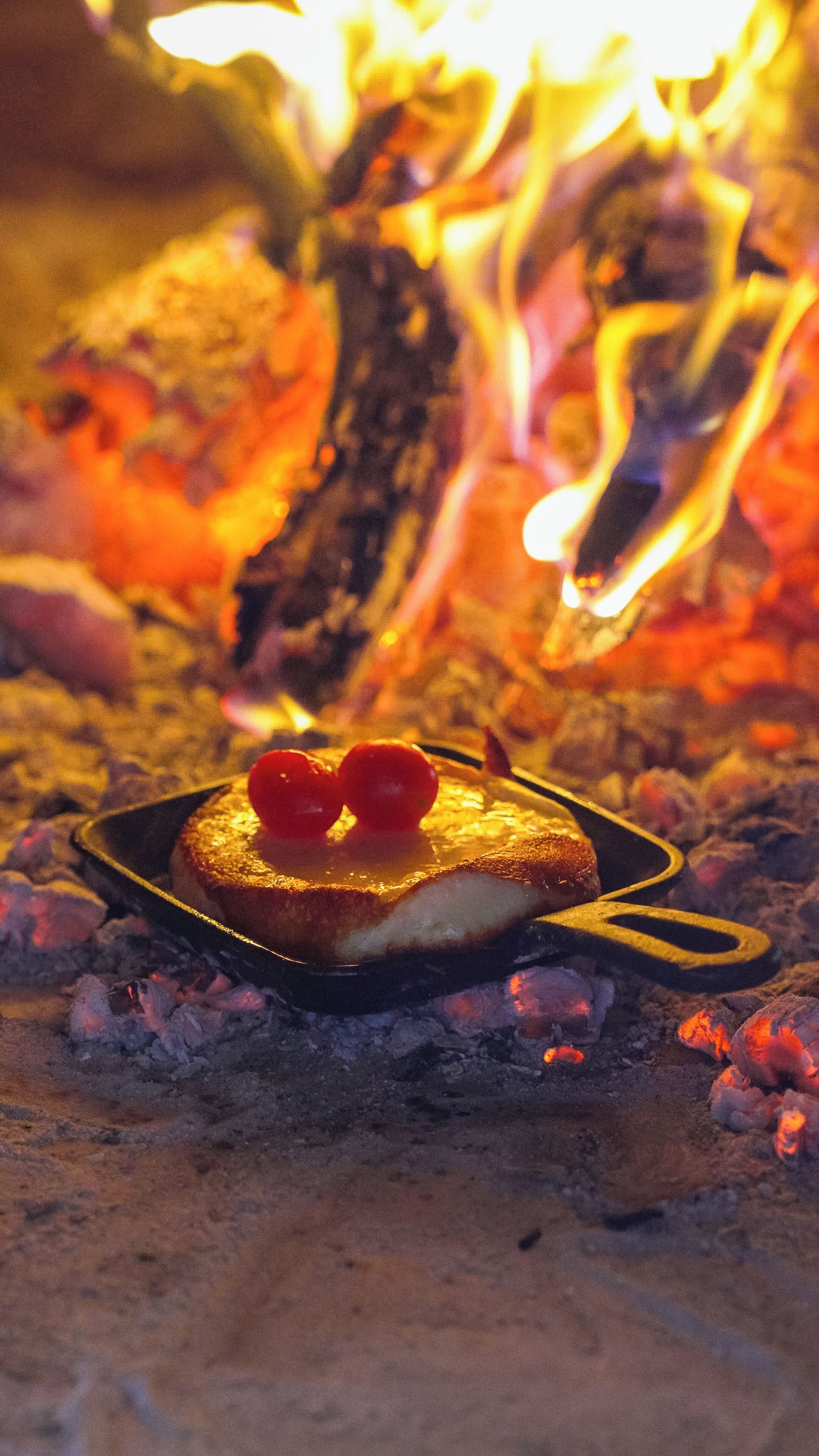 Ein gegrilltes Käsesandwich in einer Bratpfanne mit Tomaten auf einer Glutbett.