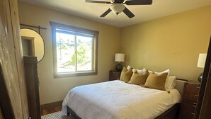 Ein Schlafzimmer mit Bett, Deckenventilator, Fenster und Nachttisch.