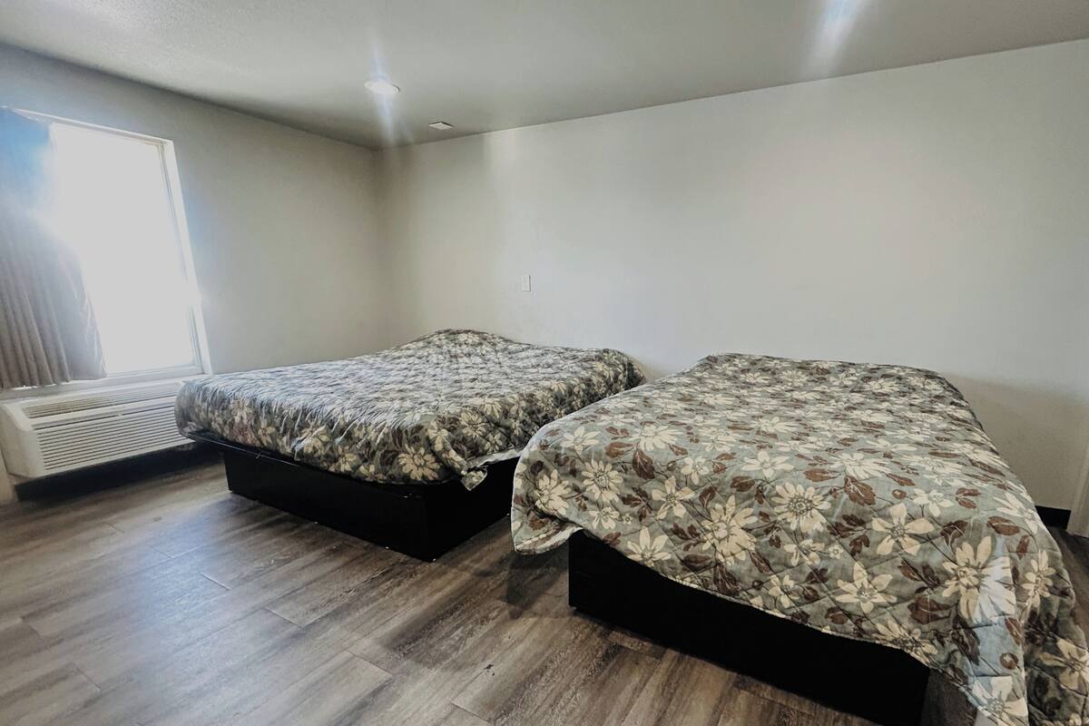 Two single beds with floral bedding in a room with wooden flooring and a window.