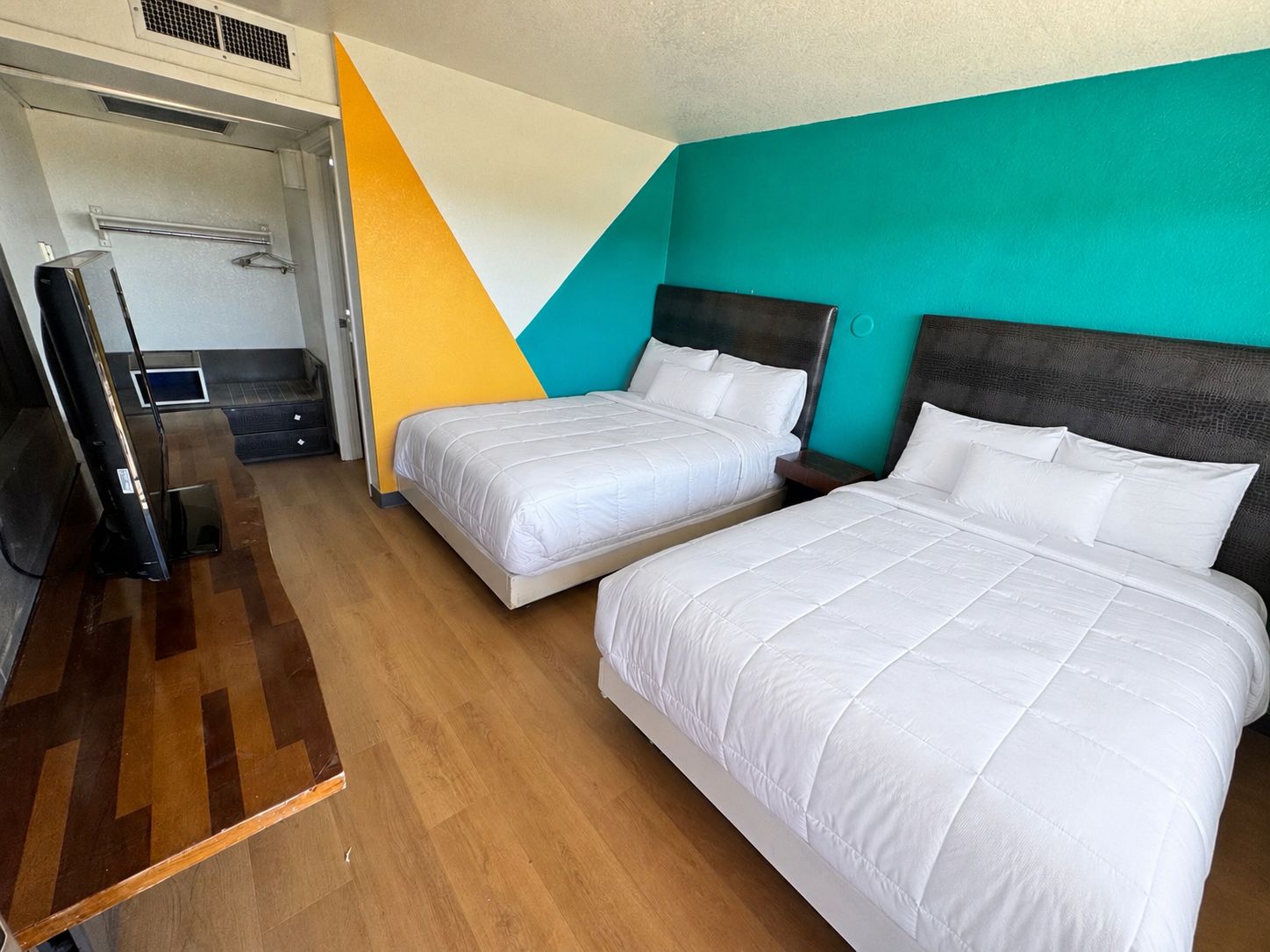 Une chambre d’hôtel avec deux lits, une télévision et un miroir.