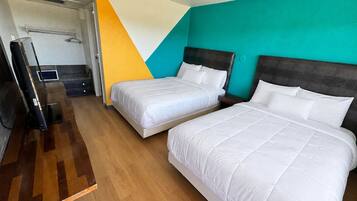 Habitación de hotel con dos camas, un televisor y un espejo.