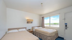 A hotel room with two beds, a window with curtains, a bedside table with a phone, and a door with a sign. - Signature Inn Socorro (Socorro)