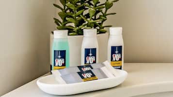 A bathroom with a white sink, a plant, and three bottles of facial bar lotion.