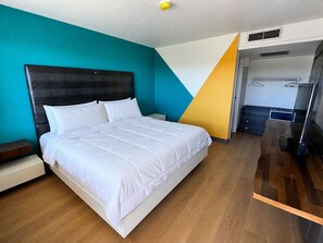 A modern hotel room with a large bed, a nightstand, a wardrobe, and a bathroom visible through an open door. - Signature Inn Socorro (Socorro)