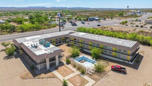 A multi-story hotel with a rooftop pool, located in a desert setting with a clear road and distant mountains. - Signature Inn Socorro (Socorro)