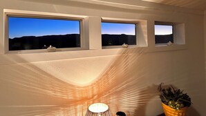 Una habitación con tres ventanas alineadas horizontalmente, cada una con vistas a un paisaje montañoso.