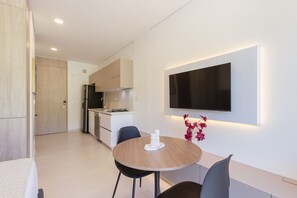 A modern kitchen with a dining area, a flat-screen TV mounted on the wall, and a small table with chairs. - U-GO Delventto - Pozos Colorados (Santa Marta)