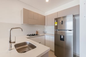 A modern kitchen with a stainless steel refrigerator, a gas stove, and a sink. - U-GO Delventto - Pozos Colorados (Santa Marta)
