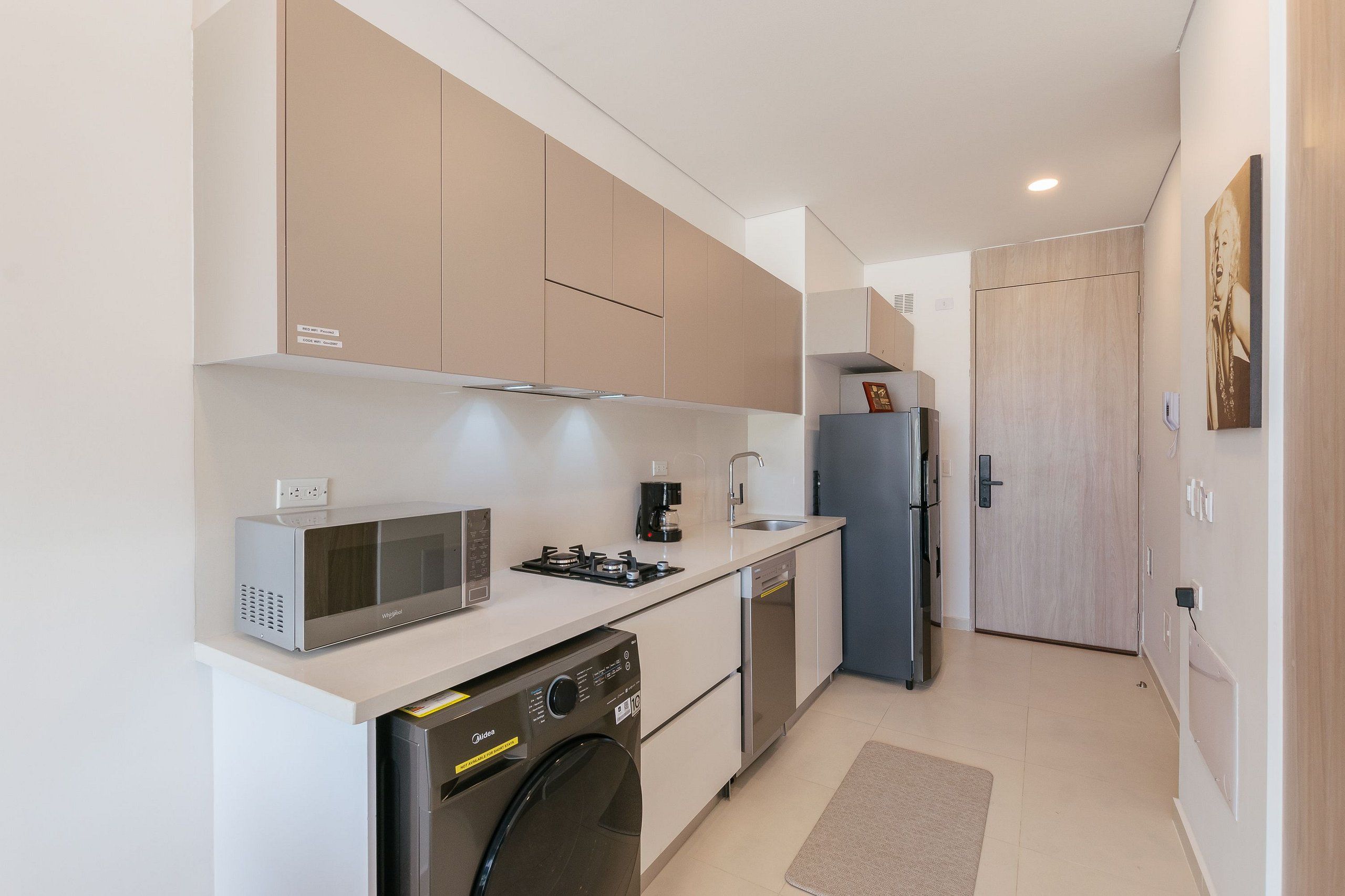 A compact kitchen with a microwave, stove, coffee maker, dishwasher, and a washing machine.