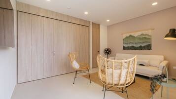 A modern living room with a sofa, two wicker chairs, a wall-mounted artwork, and a floor lamp.