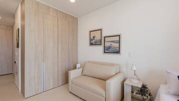 Uma sala de estar moderna com um sofá, uma mesa pequena com um abajur e duas fotografias emolduradas na parede.