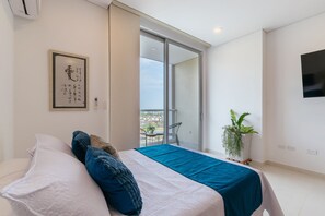 Una camera da letto moderna con un letto, una porta scorrevole in vetro che dà su un balcone, una TV a parete e una pianta in vaso.