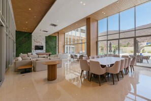 Un interior espacioso y moderno con un amplio comedor, asientos confortables y un muro verde decorativo.
